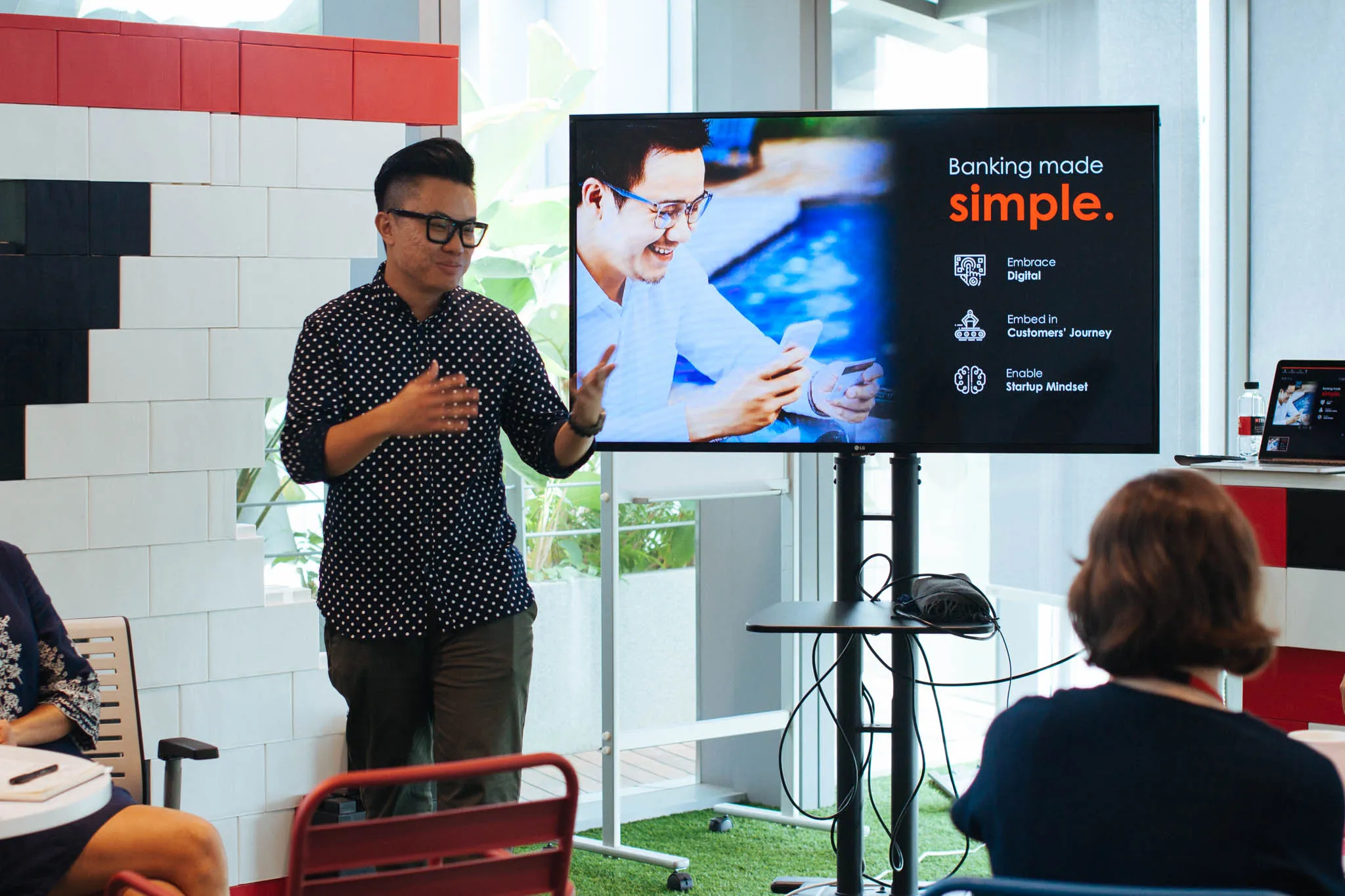 Presenter standing beside a screen that reads Banking made simple while an audience watches