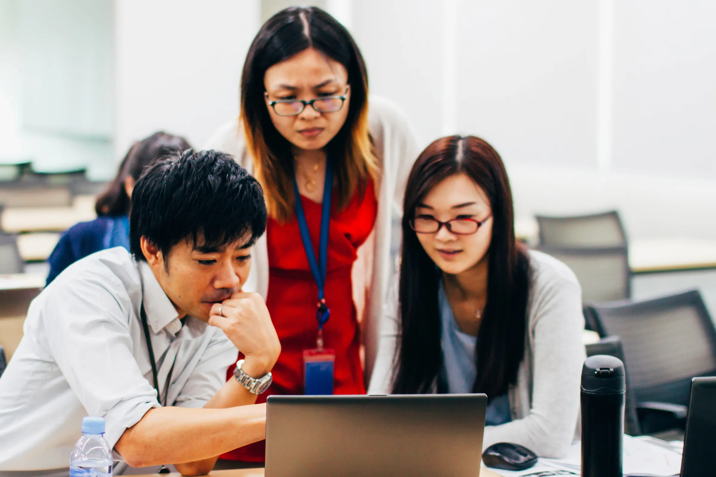 Four colleagues looking at a laptop together in an office