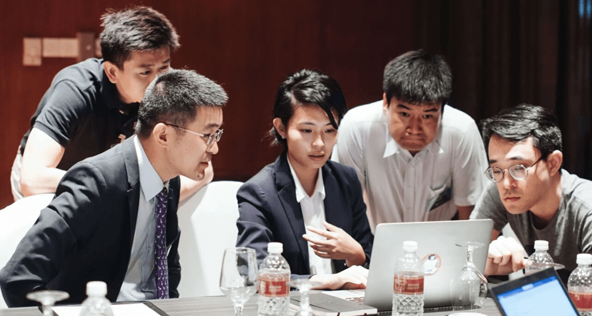 Doctors gathered around a laptop during group coaching at the Abbott communication hackathon