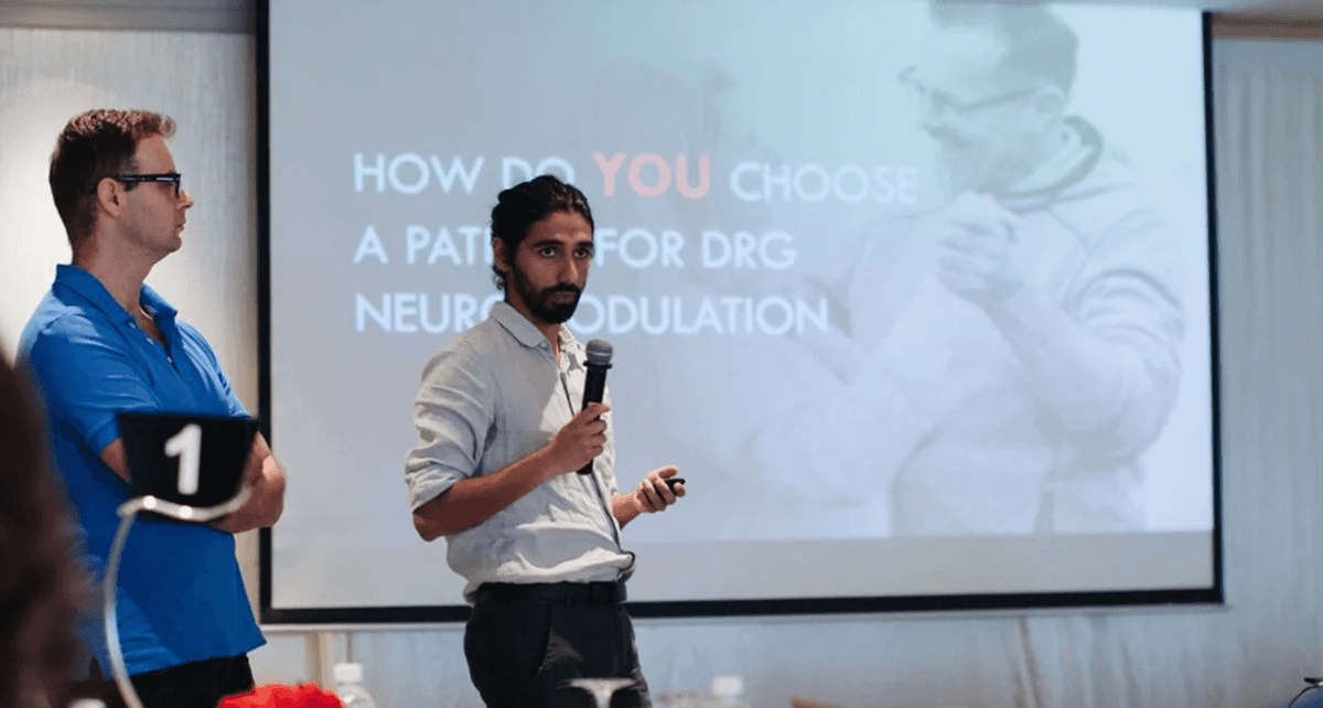 A workshop participant presenting confidently with a microphone in front of a slide during the final presentation session