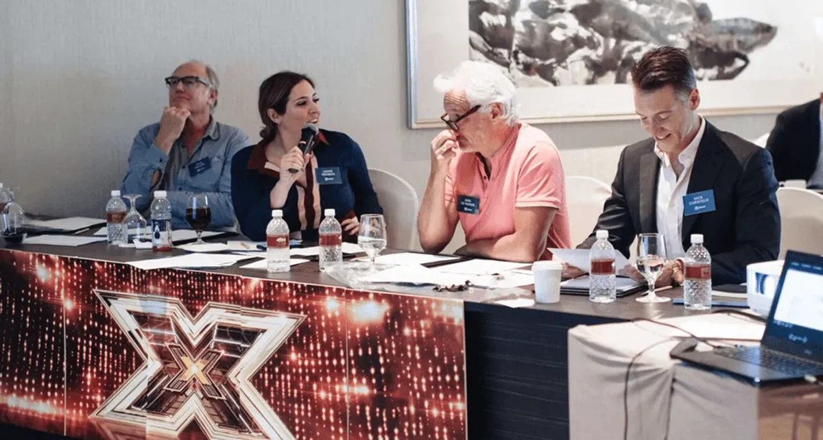 Four panellists seated at a table with name cards and water bottles, one speaking into a microphone
